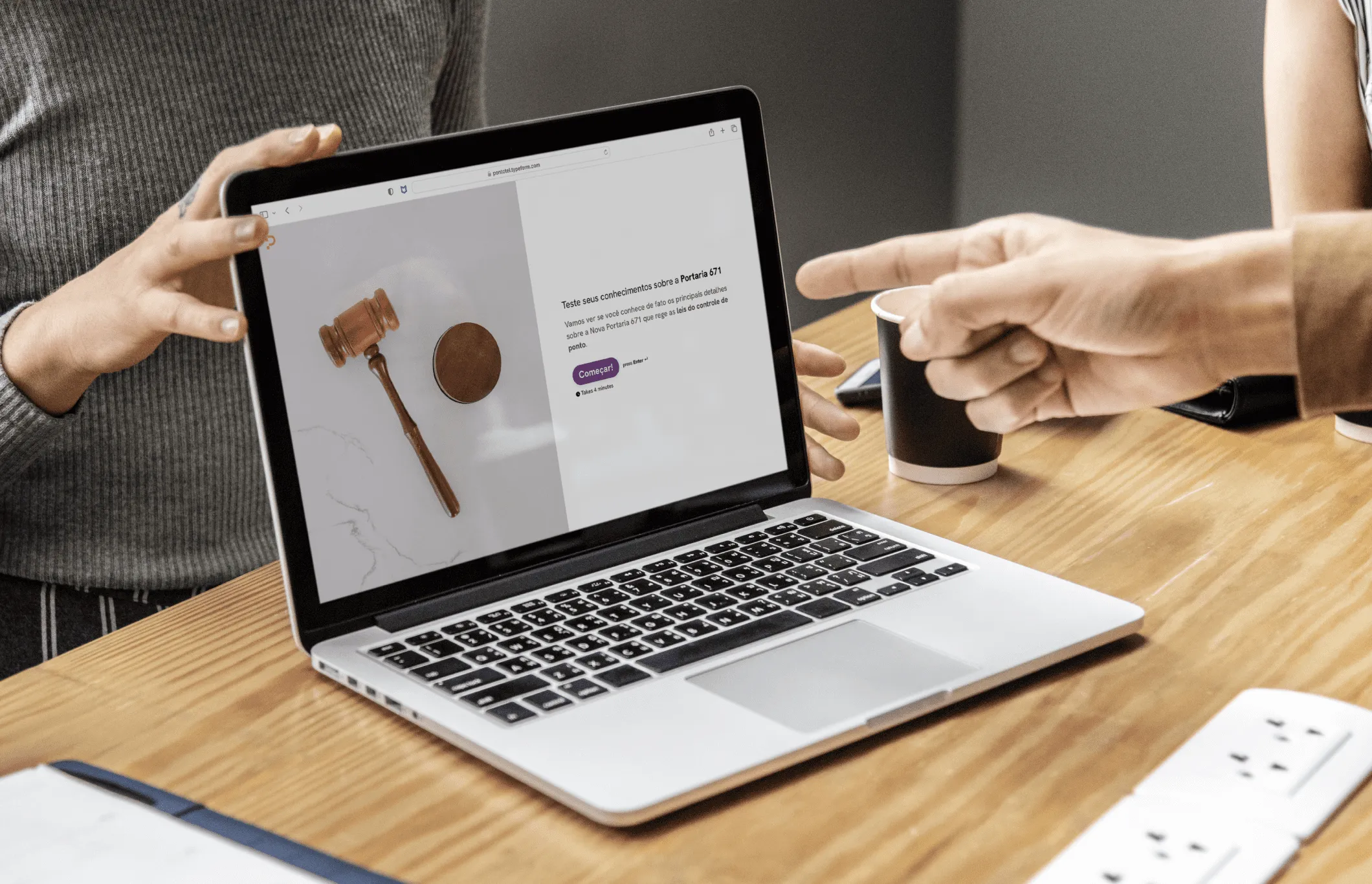 Pessoa apontando para notebook sobre uma mesa
