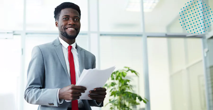 imagem de um homem sorrindo segurando folhas de papel