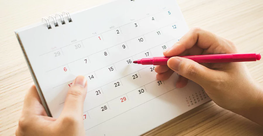 Mãos segurando um calendário e uma caneta